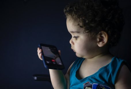 boy in blue tank top holding smartphone