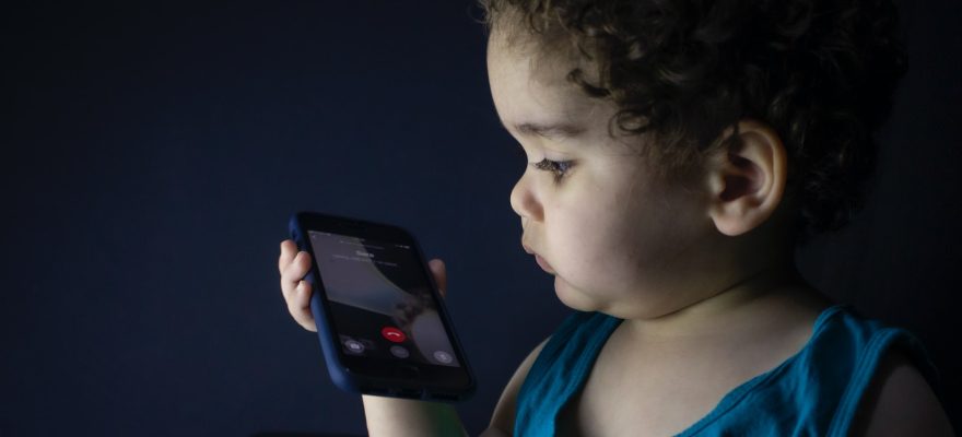 boy in blue tank top holding smartphone