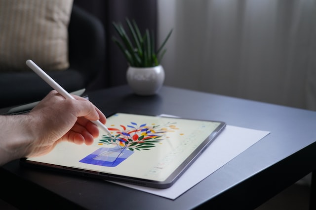 person holding white pencil writing on ipad