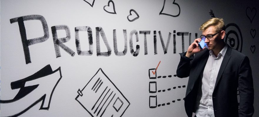 man holding smartphone looking at productivity wall decor