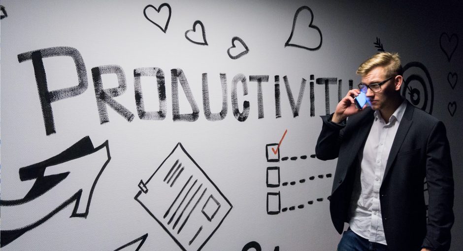 man holding smartphone looking at productivity wall decor